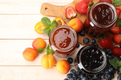 Photo of Different jams in jars and ingredients on white wooden table, flat lay