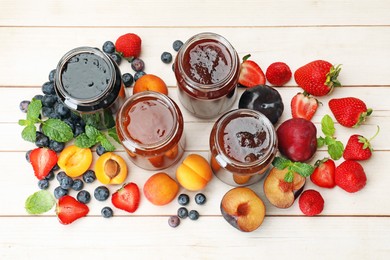 Photo of Different jams in jars and ingredients on white wooden table, flat lay