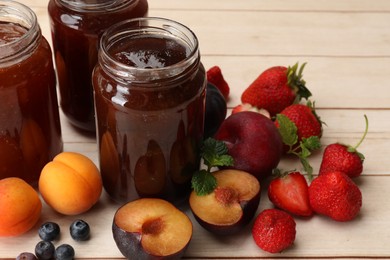 Photo of Different jams in jars and ingredients on white wooden table, closeup