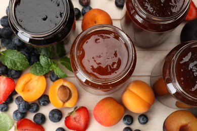 Photo of Different jams in jars and ingredients on white wooden table, flat lay