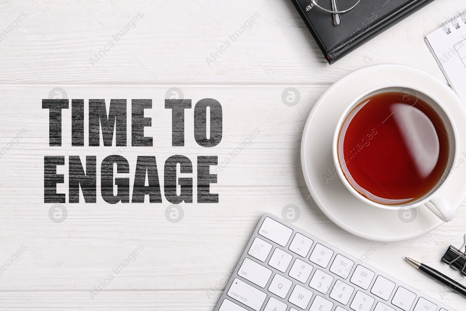 Time to engage. Cup of tea, computer keyboard and stationery on white wooden table, flat lay Image of Time to engage. Cup of tea, computer keyboard and stationery on white wooden table, flat lay