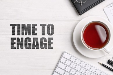 Image of Time to engage. Cup of tea, computer keyboard and stationery on white wooden table, flat lay