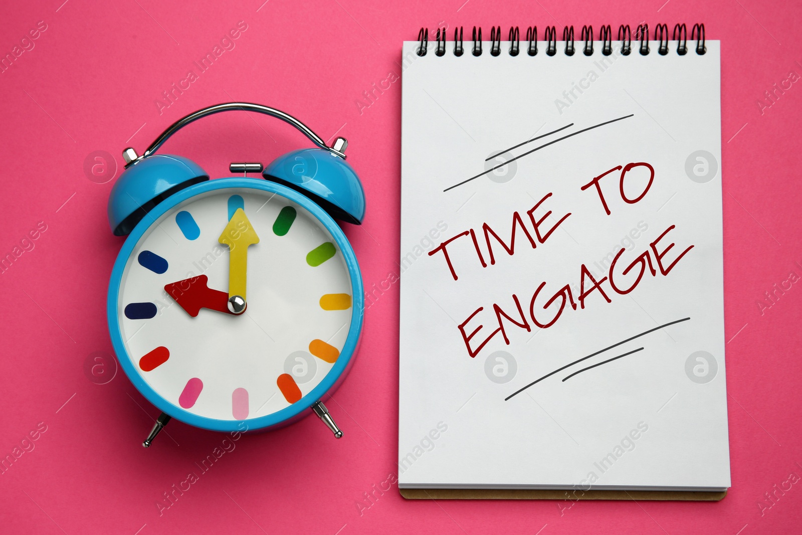 Time To Engage phrase written in notebook and alarm clock on pink background, top view Image of Time To Engage phrase written in notebook and alarm clock on pink background, top view
