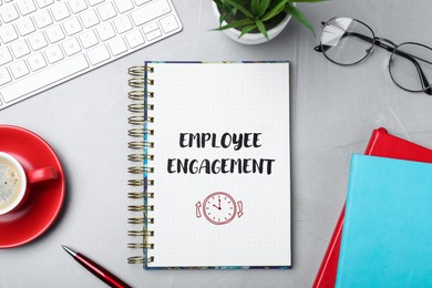 Image of Employee engagement. Words and drawing in notebook on office desk, top view