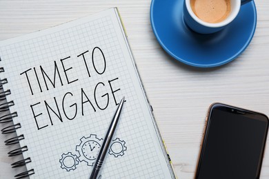 Image of Time to engage. Words and drawing in notebook, coffee and mobile phone on white wooden table, top view