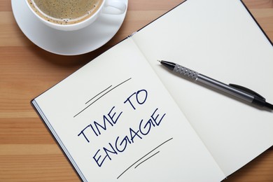 Image of Time To Engage phrase written in notebook and coffee on wooden desk, top view