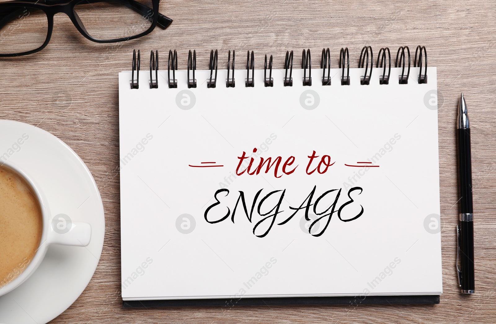 Time To Engage phrase written in notebook, pen and coffee on wooden desk, top view Image of Time To Engage phrase written in notebook, pen and coffee on wooden desk, top view