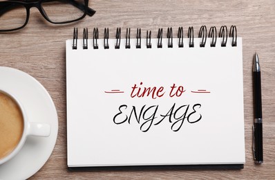 Image of Time To Engage phrase written in notebook, pen and coffee on wooden desk, top view