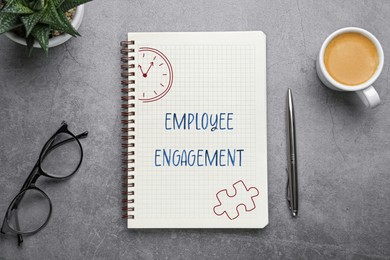 Image of Employee engagement. Words and drawings in notebook, pen and coffee on grey table, top view