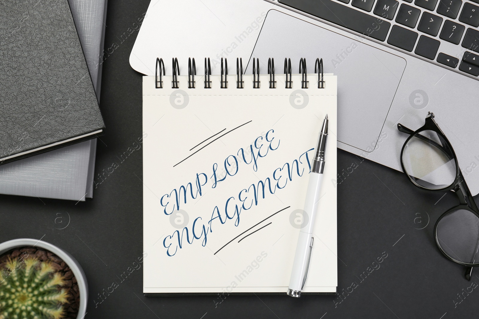 Employee engagement. Words in notebook, pen and laptop on black table, top view Image of Employee engagement. Words in notebook, pen and laptop on black table, top view