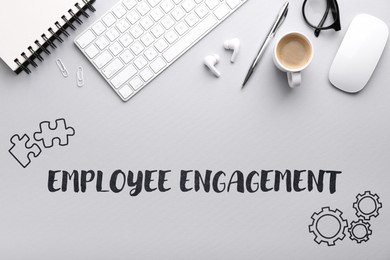 Image of Employee engagement. Office workplace with coffee, stationery and computer keyboard on grey table. top view