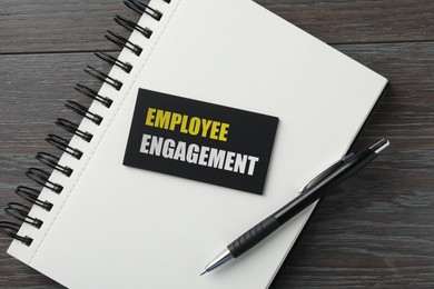 Image of Business card with words Employee Engagement, notebook and pen on wooden table, top view