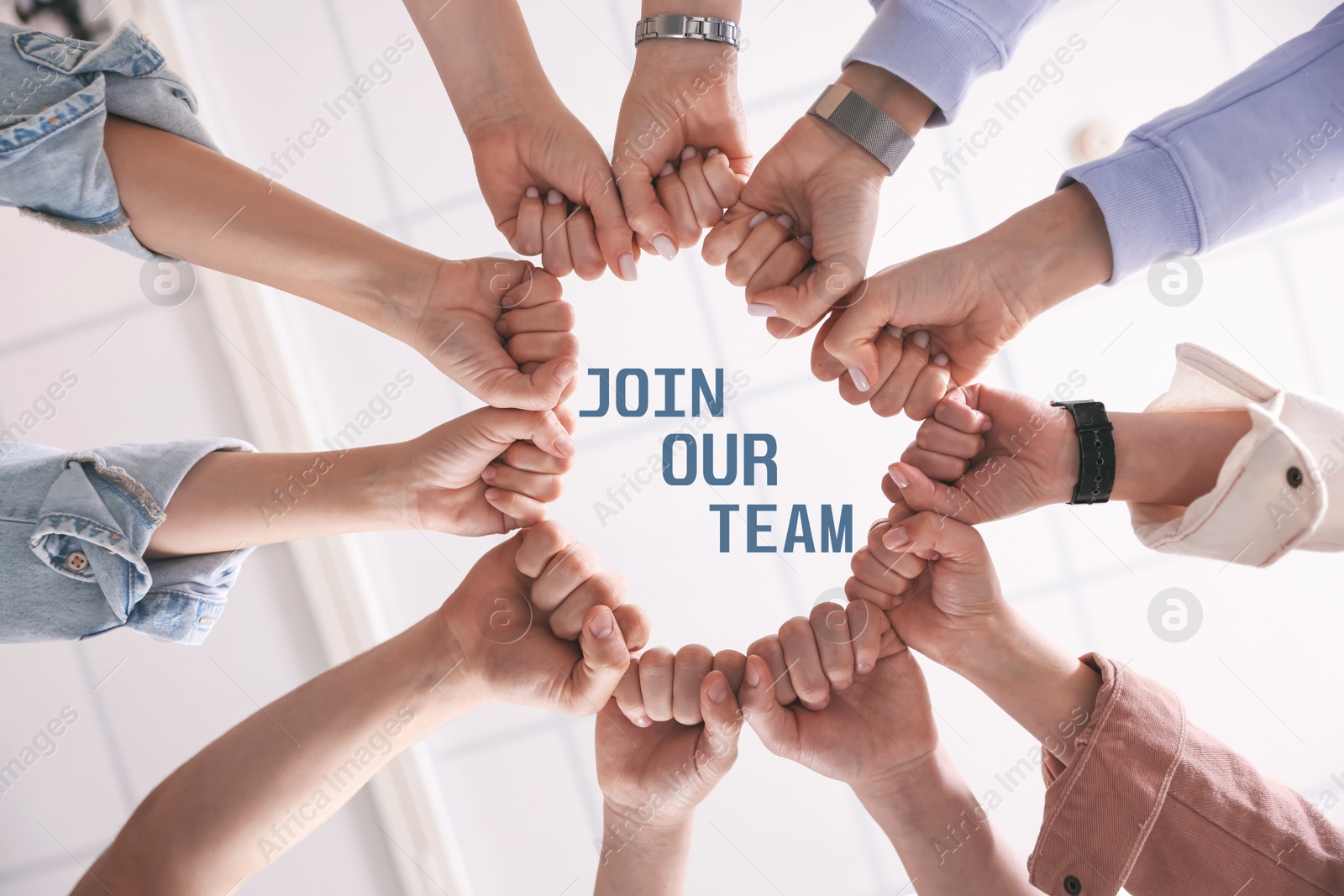 Join Our Team. Group of people holding fists together indoors, bottom view. Employee search, recruitment concept Image of Join Our Team. Group of people holding fists together indoors, bottom view. Employee search, recruitment concept