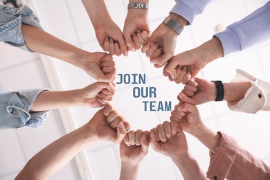 Image of Join Our Team. Group of people holding fists together indoors, bottom view. Employee search, recruitment concept