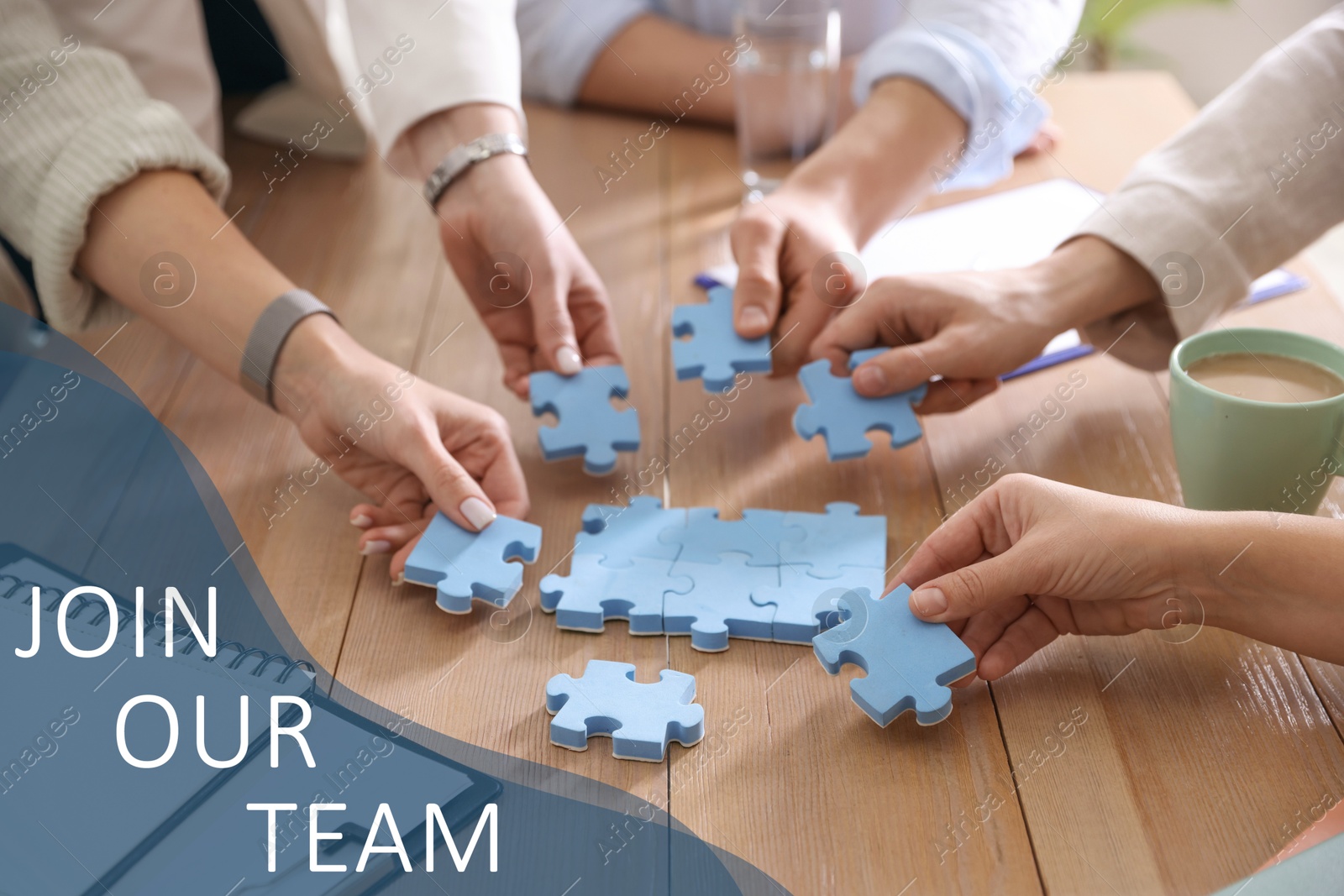 Join Our Team. Group of people putting puzzle pieces together at wooden table indoors, closeup. Employee search, recruitment concept Image of Join Our Team. Group of people putting puzzle pieces together at wooden table indoors, closeup. Employee search, recruitment concept