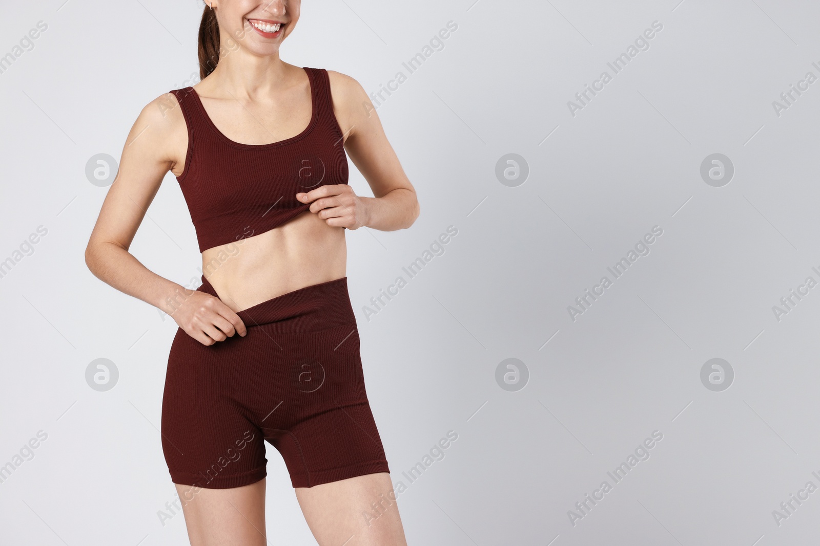 Woman with flat belly on gray background closeup. Space for text Photo of Woman with flat belly on gray background closeup. Space for text