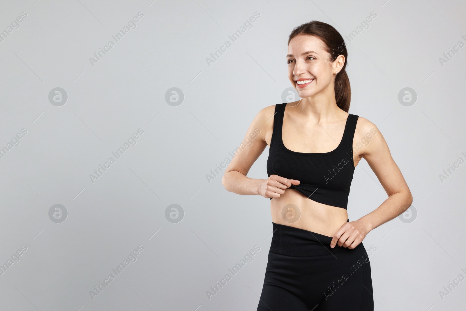 Beautiful woman with flat belly on gray background, space for text Photo of Beautiful woman with flat belly on gray background, space for text