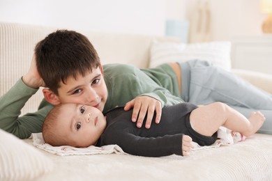 Photo of Cute little brothers on sofa at home