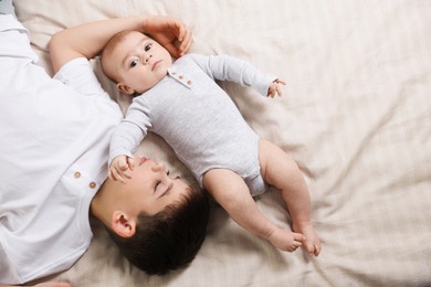Photo of Cute little brothers on bed, top view