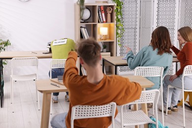 Photo of Schoolmates bullying teenage girl with sign You Loser on her back at school
