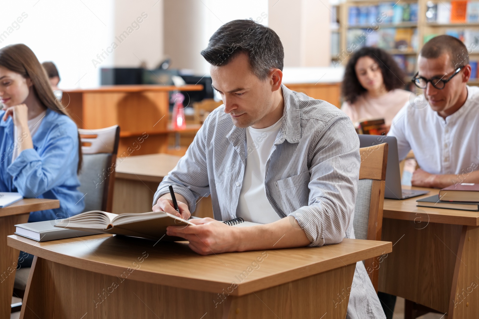 Photo of People studying at desks in public library, selective focus