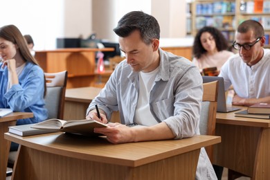 Photo of People studying at desks in public library, selective focus