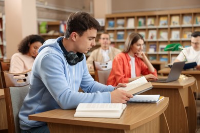 Photo of People studying at desks in public library, selective focus
