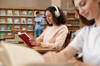 Photo of People studying in public library, selective focus