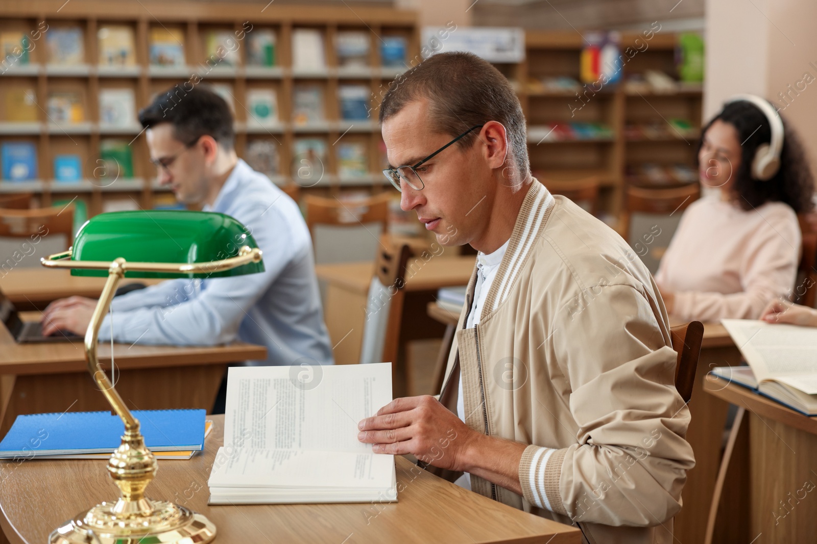 Photo of People studying at desks in public library, selective focus