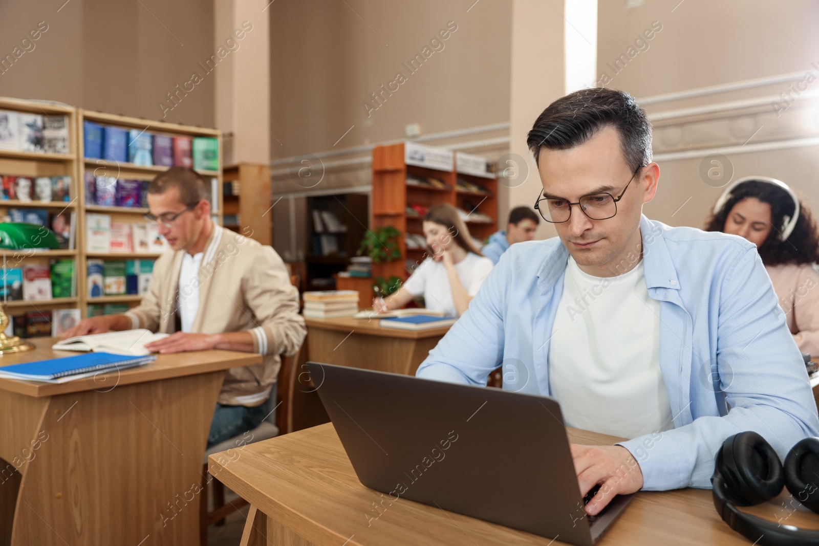 People studying at desks in public library, selective focus Photo of People studying at desks in public library, selective focus