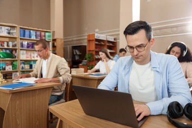 Photo of People studying at desks in public library, selective focus