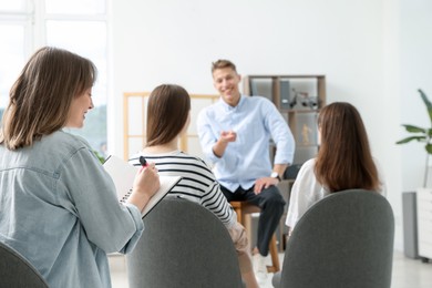 Photo of Group of people having meeting during life coaching class indoors, selective focus