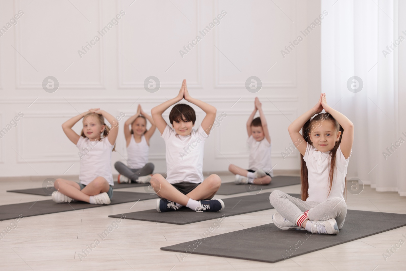 Group of children practicing yoga on mats in class Photo of Group of children practicing yoga on mats in class