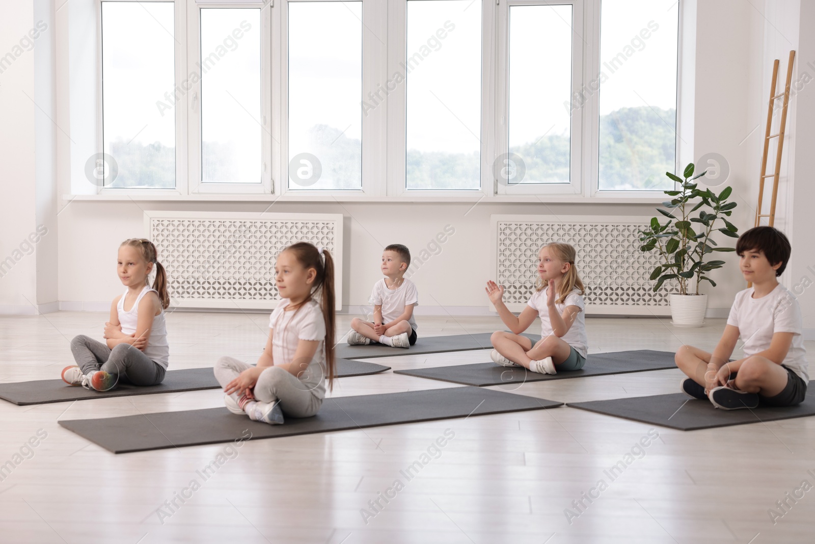 Group of children practicing yoga on mats in class Photo of Group of children practicing yoga on mats in class