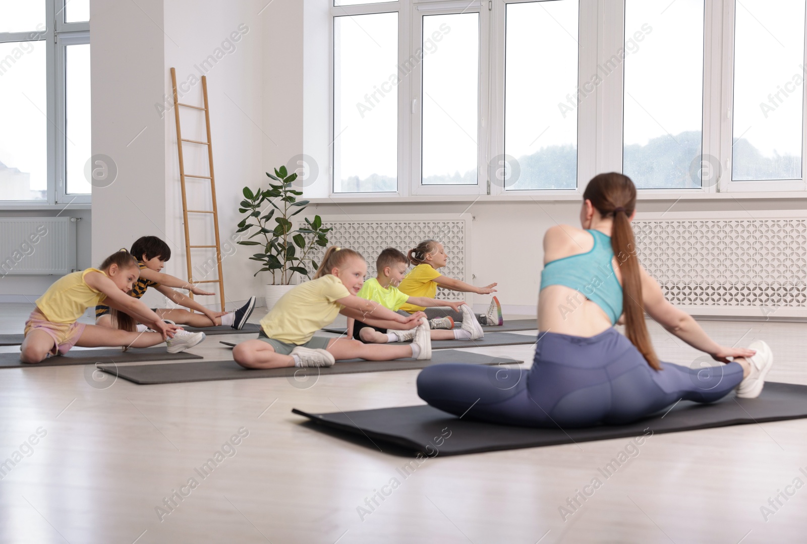 Photo of Group of children practicing yoga with coach on mats in class