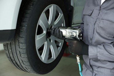 Photo of Mechanic changing tire at car service, closeup