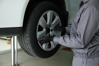 Photo of Mechanic changing tire at car service, closeup
