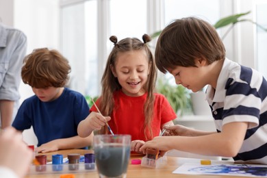 Photo of Kids painting at table indoors. Learning to draw
