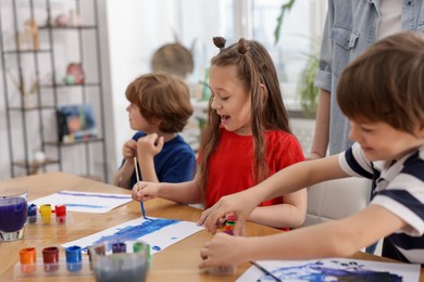 Photo of Kids with teacher at painting lesson. Learning to draw