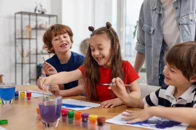 Photo of Kids with teacher at painting lesson. Learning to draw