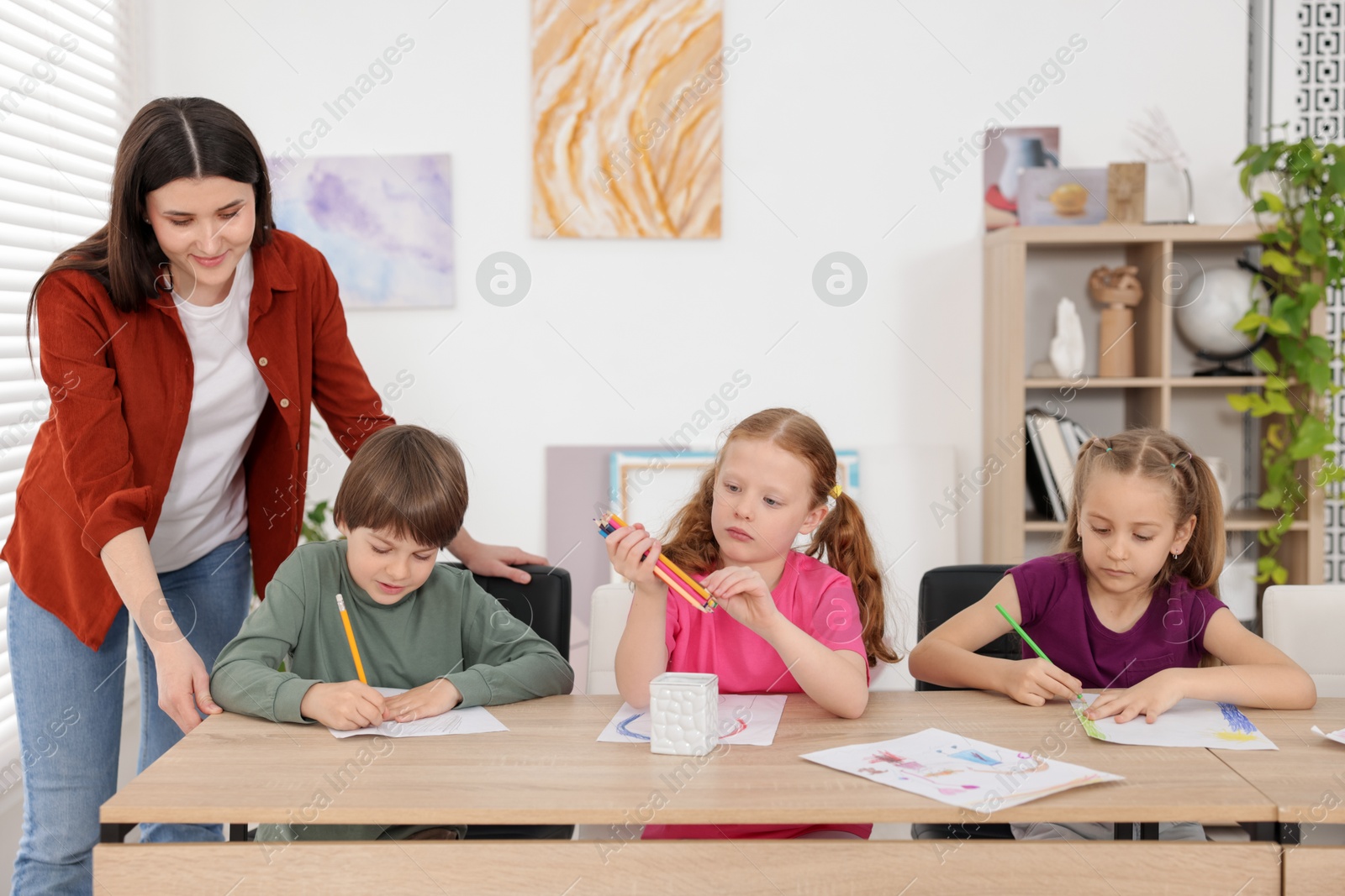 Woman teaching kids to draw at painting lesson indoors Photo of Woman teaching kids to draw at painting lesson indoors