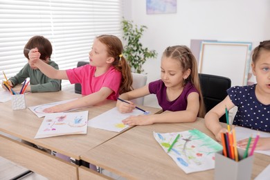 Photo of Kids painting at table indoors. Learning to draw