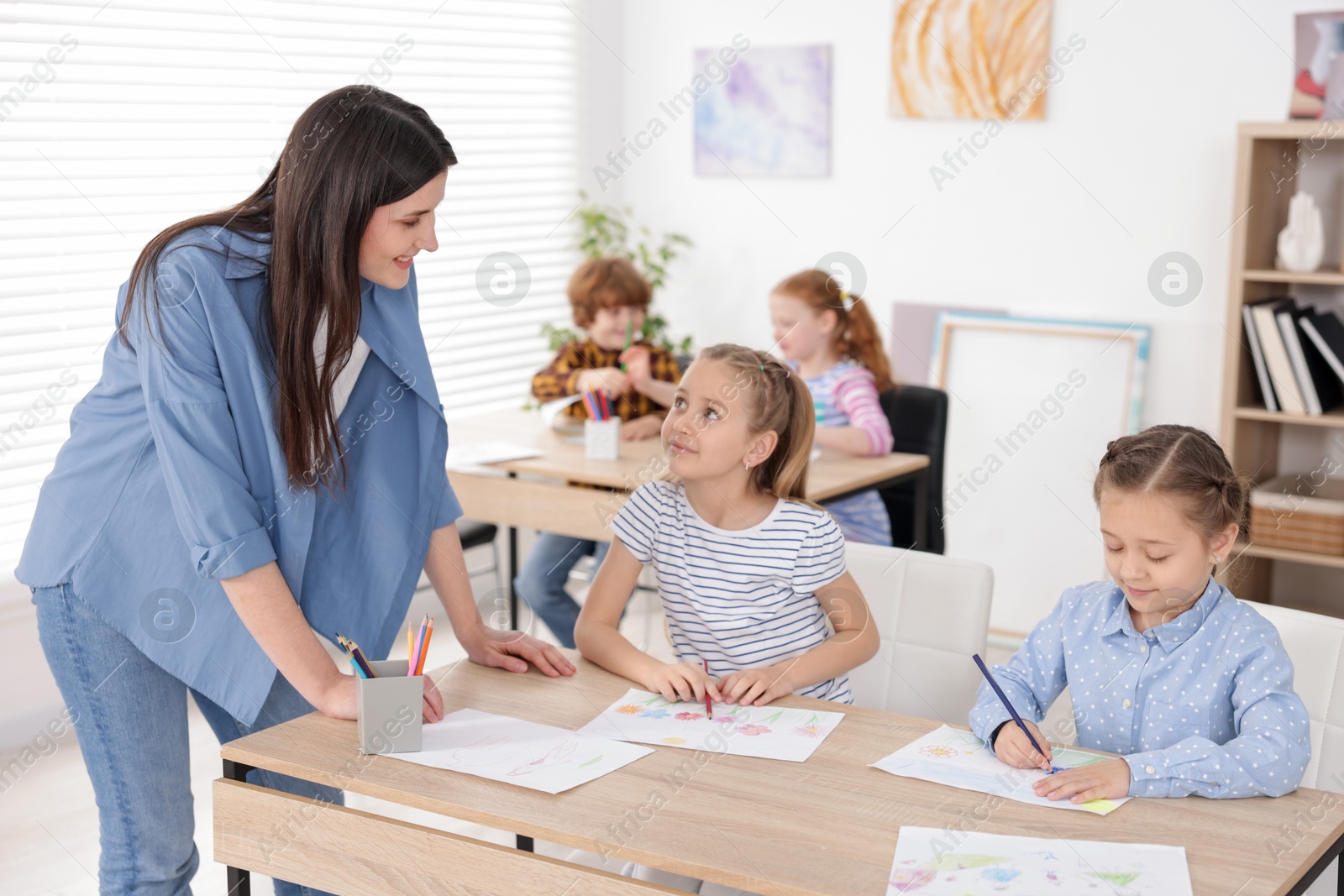 Woman teaching kids to draw at painting lesson indoors, selective focus Photo of Woman teaching kids to draw at painting lesson indoors, selective focus