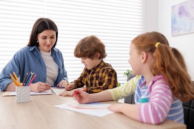 Photo of Woman teaching kids to draw at painting lesson indoors