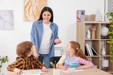 Photo of Woman teaching kids to draw at painting lesson indoors