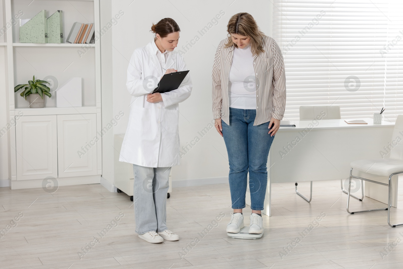 Weight loss. Overweight woman standing on scales during consultation with nutritionist in clinic Photo of Weight loss. Overweight woman standing on scales during consultation with nutritionist in clinic