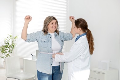 Photo of Weight loss. Nutritionist measuring happy overweight woman's waist with tape in clinic