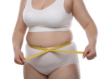Photo of Weight loss. Plus size woman measuring waist with tape on white background, closeup