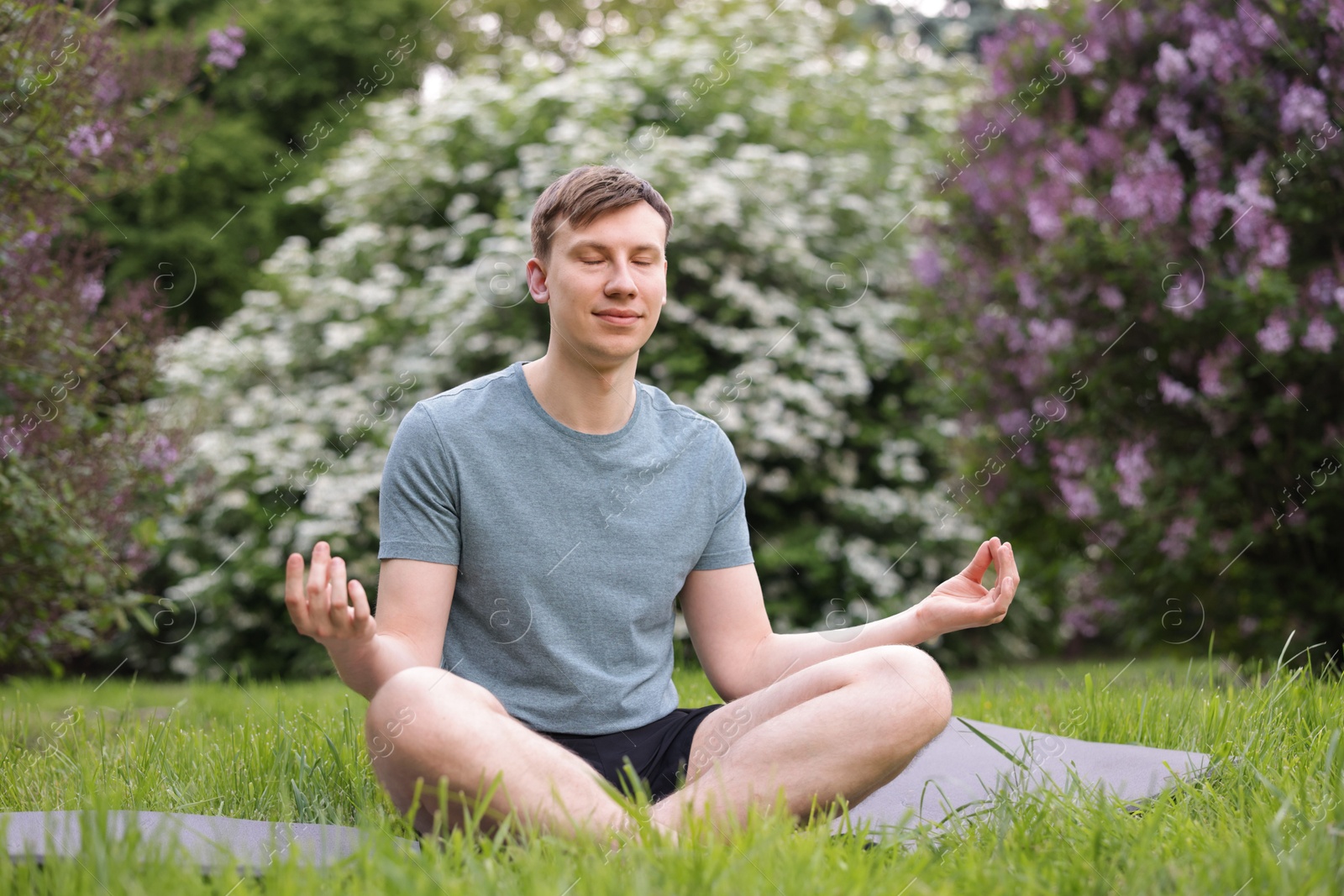 Photo of Young man practicing yoga on mat in park