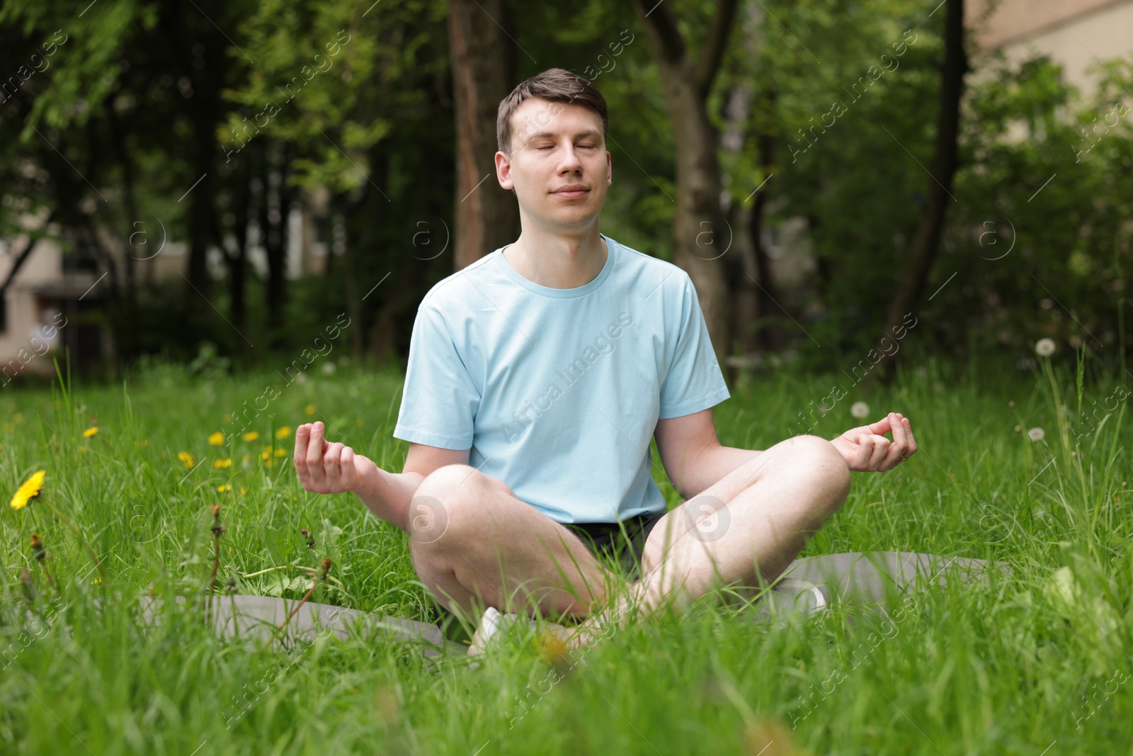 Young man practicing yoga on mat in park Photo of Young man practicing yoga on mat in park